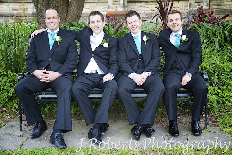 Groom sitting with groomsmen on bench in garden -wedding photography sydney